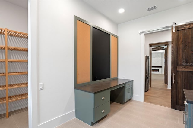 unfurnished office with recessed lighting, visible vents, baseboards, and a barn door