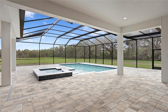 pool with a patio area, glass enclosure, and an in ground hot tub