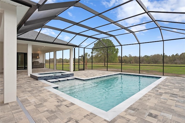 view of pool with a patio, a pool with connected hot tub, an outdoor kitchen, and glass enclosure