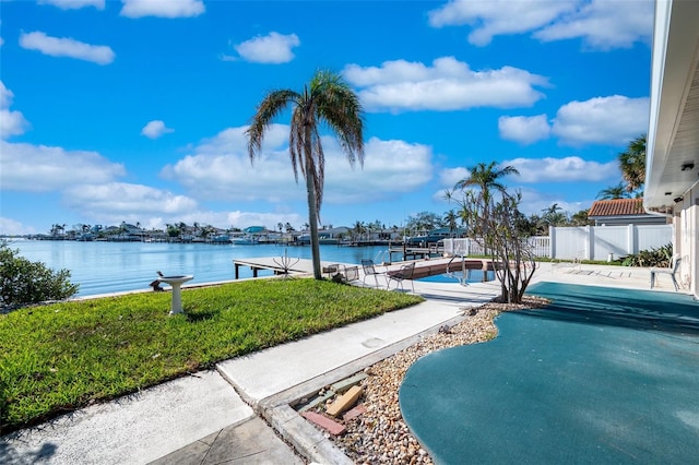 view of swimming pool with a yard, a water view, and a boat dock