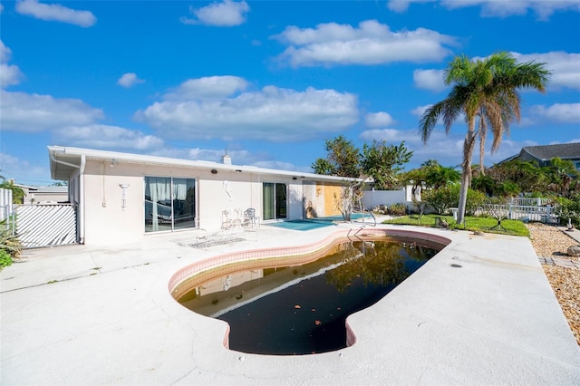 rear view of property featuring a fenced in pool and a patio area