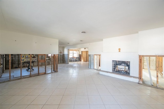 unfurnished living room with light tile patterned floors and a brick fireplace