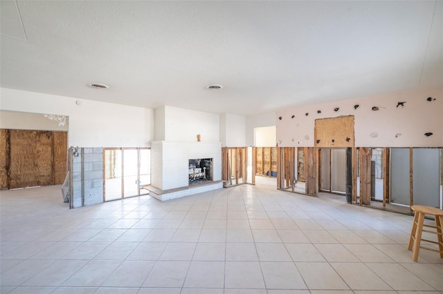 unfurnished living room with a fireplace and light tile patterned floors