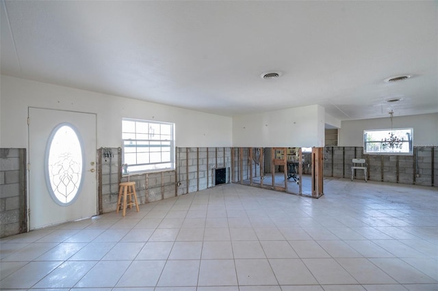 unfurnished living room featuring a healthy amount of sunlight, light tile patterned floors, and tile walls