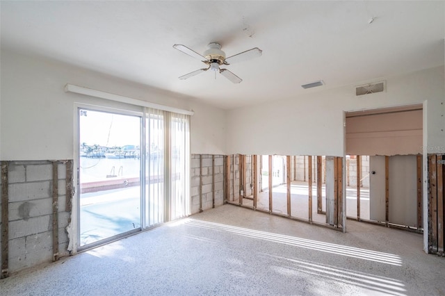 unfurnished room featuring ceiling fan and a water view