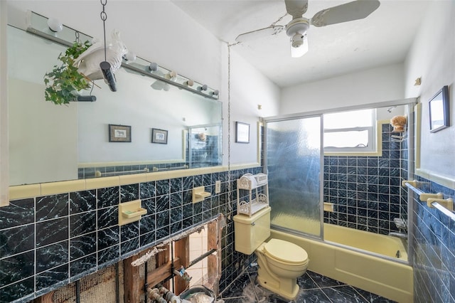 bathroom with ceiling fan, bath / shower combo with glass door, tile walls, and toilet