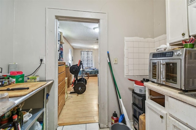 kitchen featuring white cabinets, a textured ceiling, and light hardwood / wood-style flooring