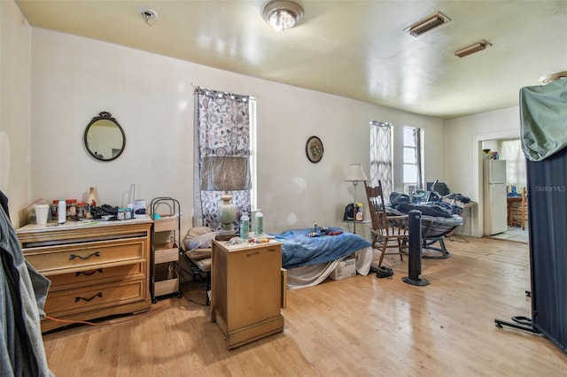 bedroom with light wood-type flooring and white fridge