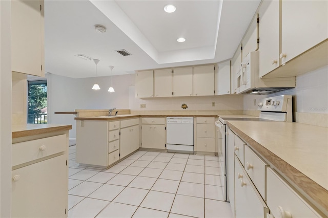 kitchen with kitchen peninsula, pendant lighting, white appliances, a tray ceiling, and light tile patterned floors