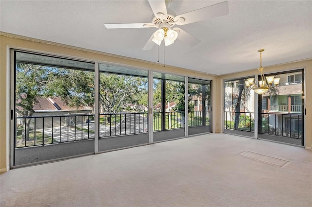 unfurnished sunroom with ceiling fan with notable chandelier and a wealth of natural light