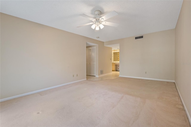 spare room featuring light carpet and ceiling fan