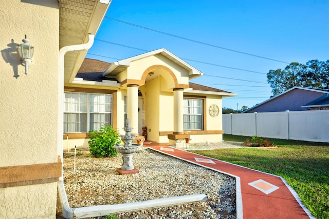 view of exterior entry featuring a lawn