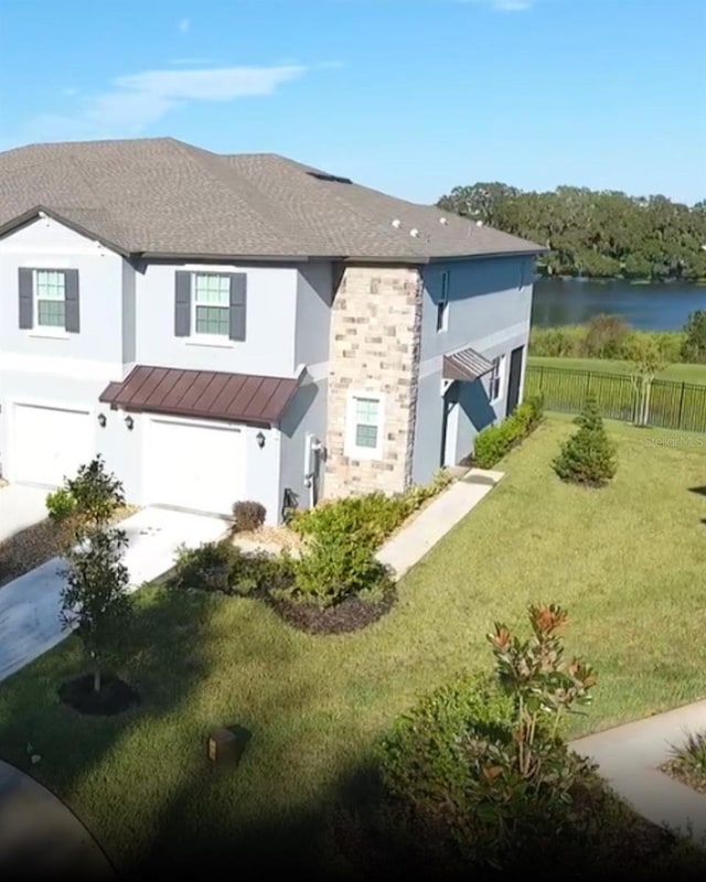 exterior space featuring a front yard, a water view, and a garage