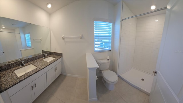 bathroom with tiled shower, tile patterned flooring, vanity, and toilet