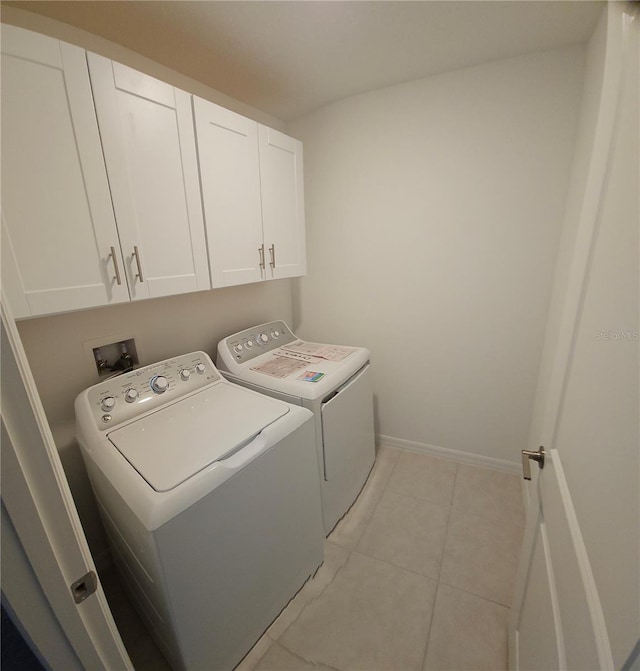 laundry room featuring washer and dryer, cabinets, and light tile patterned floors