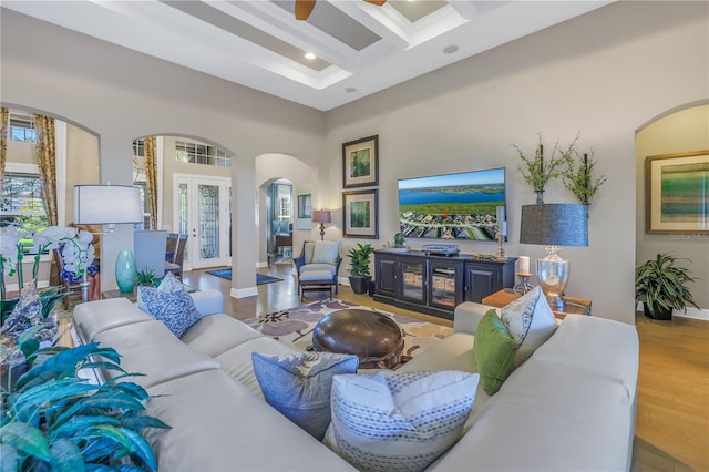 living room featuring a wealth of natural light, light hardwood / wood-style flooring, beamed ceiling, and coffered ceiling