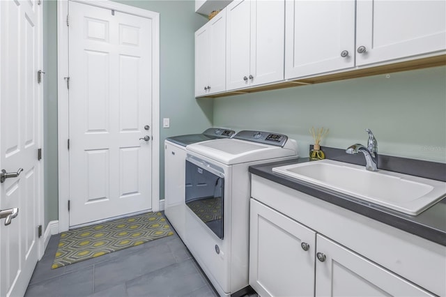 clothes washing area featuring washer and clothes dryer, cabinets, and sink