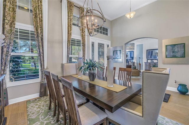 dining room with french doors, light wood-type flooring, an inviting chandelier, and ornamental molding