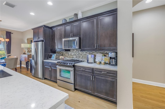 kitchen featuring appliances with stainless steel finishes, backsplash, light hardwood / wood-style floors, and dark brown cabinetry