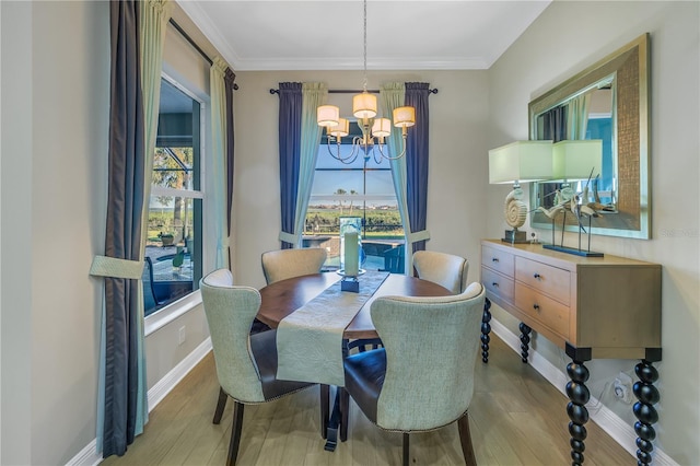 dining space featuring light hardwood / wood-style floors, ornamental molding, and an inviting chandelier