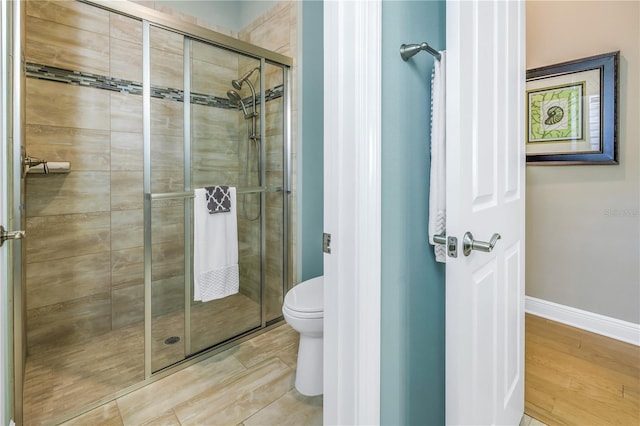 bathroom featuring toilet and a shower with door