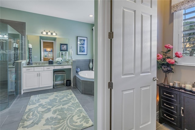 bathroom featuring vanity, a relaxing tiled tub, and tile patterned floors