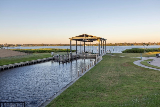 view of dock with a water view and a lawn