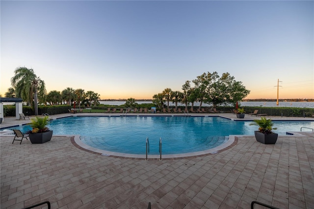 pool at dusk featuring a patio