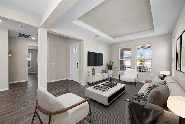 living room featuring dark hardwood / wood-style floors, a textured ceiling, and a tray ceiling