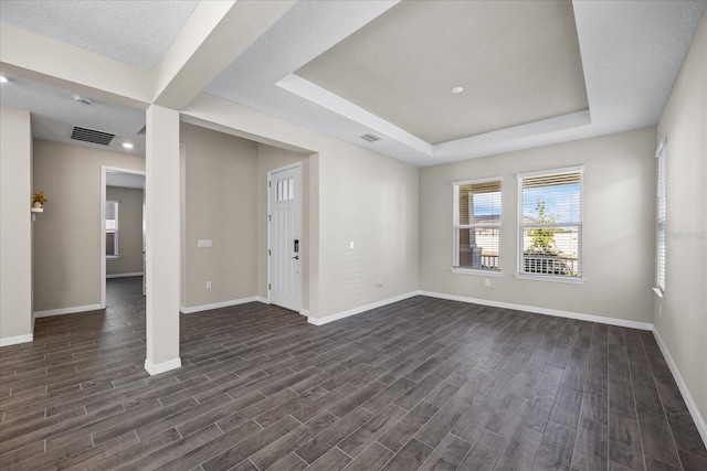 unfurnished living room with a textured ceiling, a raised ceiling, and dark wood-type flooring