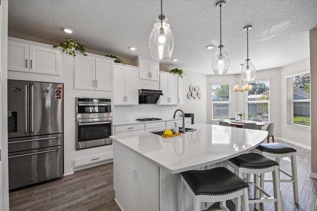 10551 Tranquil Meadow Loop, Riverview, FL 33569 - kitchen with appliances with stainless steel finishes, a sink, dark wood finished floors, an island with sink, and white cabinetry