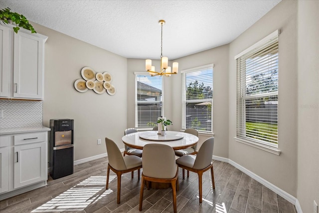 dining area featuring a textured ceiling, dark wood-type flooring, and an inviting chandelier