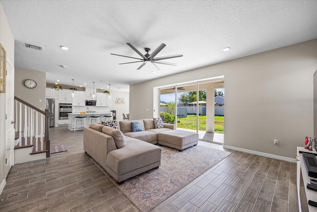 10551 Tranquil Meadow Loop, Riverview, FL 33569 - living area with wood finish floors, a ceiling fan, baseboards, stairs, and a textured ceiling