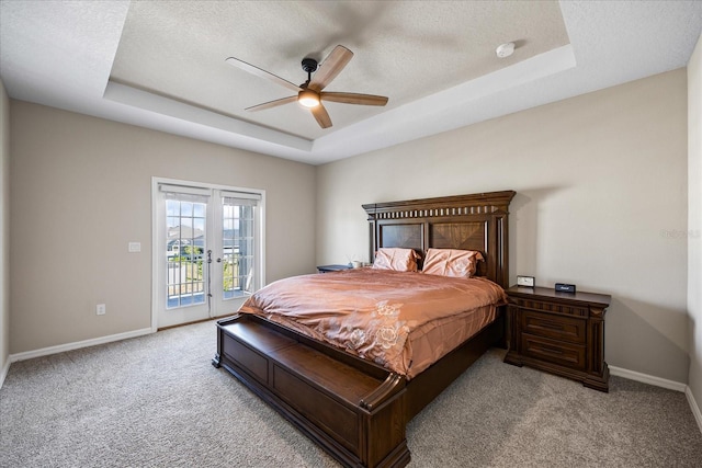 carpeted bedroom featuring french doors, a raised ceiling, ceiling fan, access to exterior, and a textured ceiling