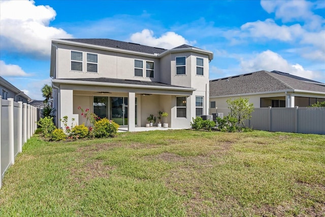 rear view of property with a lawn, ceiling fan, and cooling unit