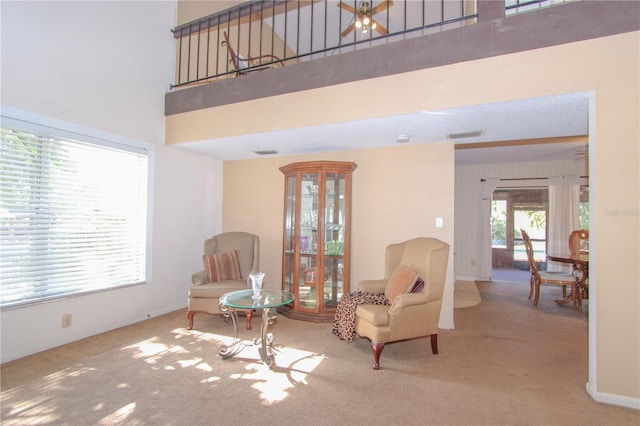 sitting room featuring carpet, plenty of natural light, ceiling fan, and a high ceiling