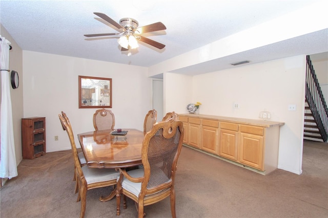 dining room featuring light carpet, ceiling fan, and a textured ceiling