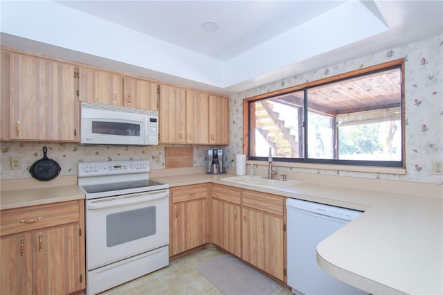 kitchen with light brown cabinets, a raised ceiling, white appliances, and sink