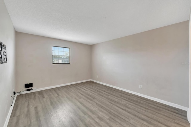 unfurnished room featuring a textured ceiling and light wood-type flooring