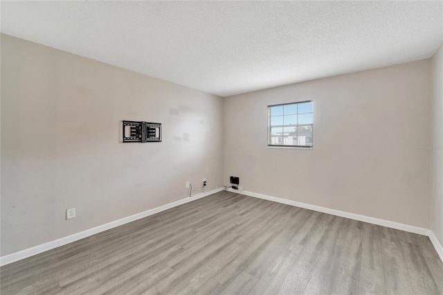 empty room featuring light wood-type flooring and a textured ceiling