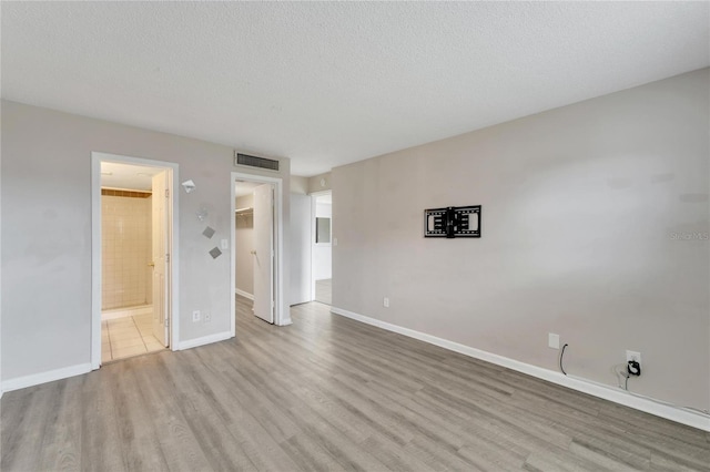 empty room featuring a textured ceiling and light hardwood / wood-style flooring