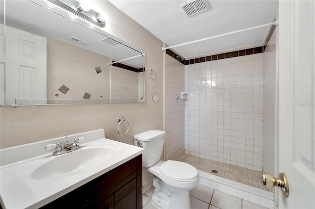 bathroom with tile patterned flooring, vanity, toilet, and tiled shower