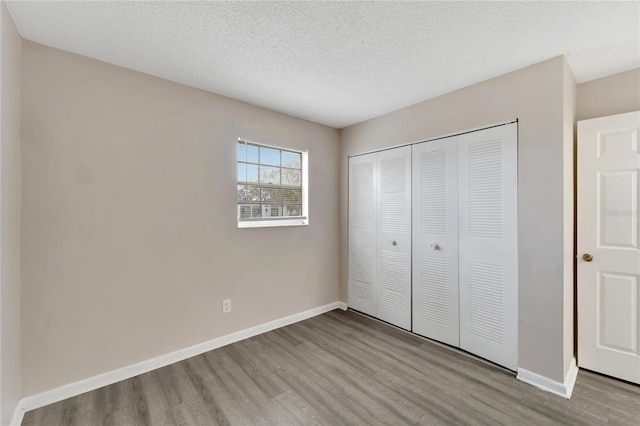 unfurnished bedroom featuring light wood-type flooring, a textured ceiling, and a closet