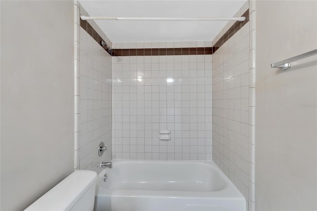 bathroom featuring tiled shower / bath combo and toilet