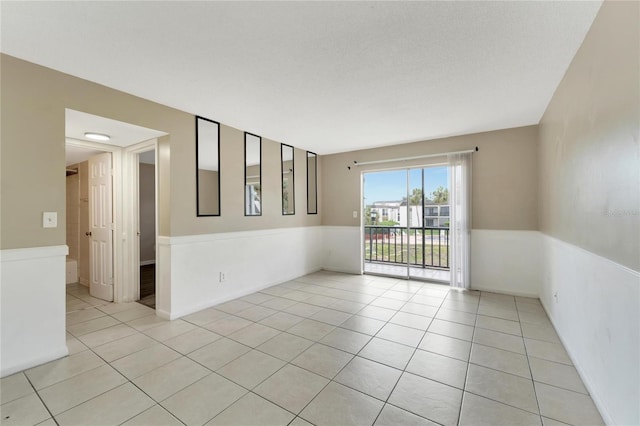 tiled empty room featuring a textured ceiling