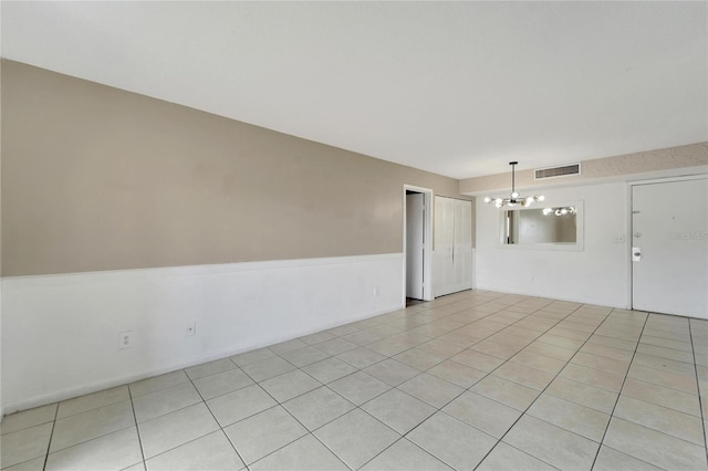 spare room with light tile patterned floors and a notable chandelier