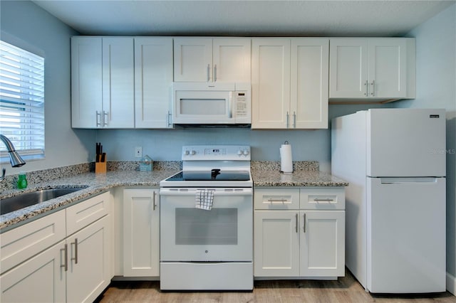 12321 Gulf Blvd, Treasure Island, FL 33706 - kitchen featuring white appliances, a sink, light wood-style floors, and white cabinets