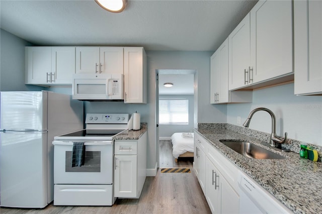 12321 Gulf Blvd, Treasure Island, FL 33706 - kitchen with white appliances, a sink, light wood-type flooring, and white cabinetry