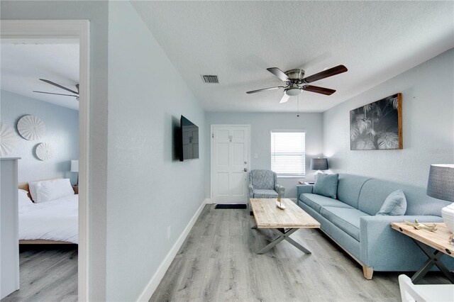 12321 Gulf Blvd, Treasure Island, FL 33706 - living room featuring a ceiling fan, light wood-type flooring, a textured ceiling, and baseboards