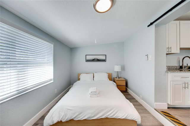 12321 Gulf Blvd, Treasure Island, FL 33706 - bedroom with light wood-style floors, baseboards, a sink, and lofted ceiling